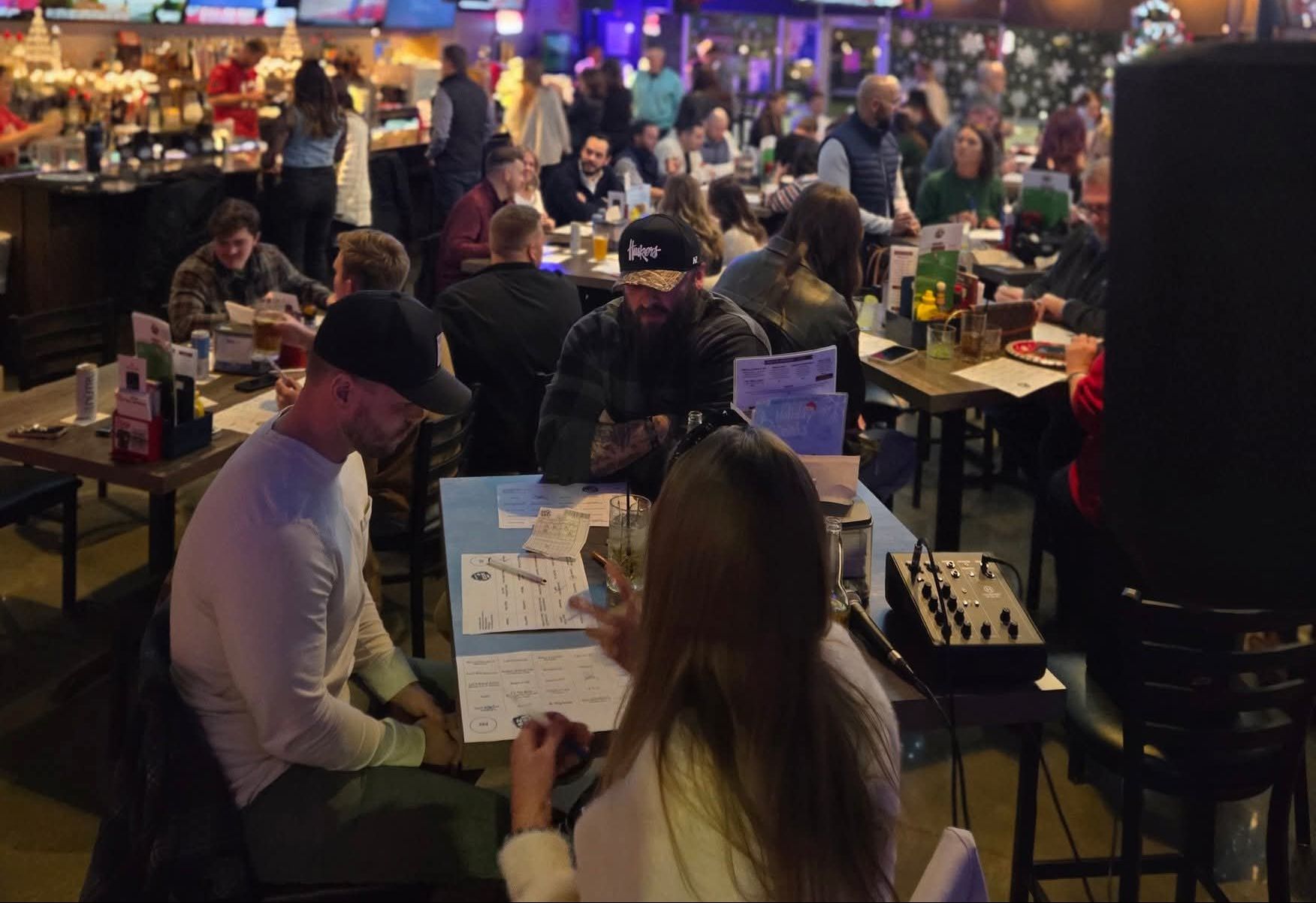 A packed bar with crowds playing Music Bingo on the venue TVs